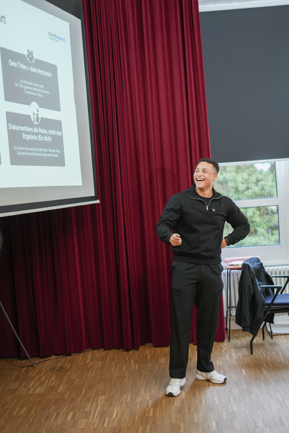 Marco Bednarz laughing on stage next to his slides